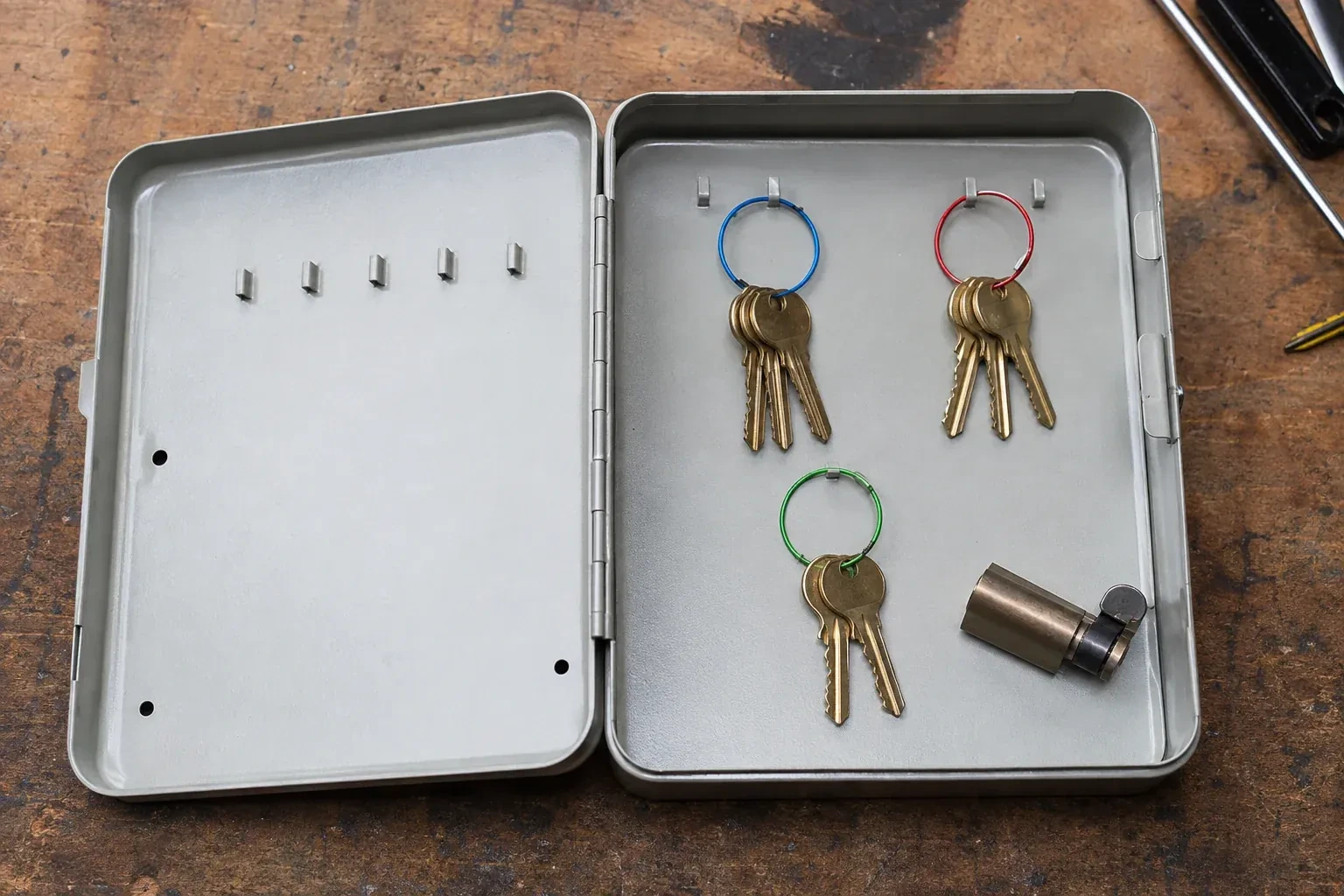 Three groups of keys on colored rings in an open metal key cabinet. — Master Key System Design, Guelph